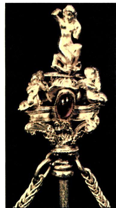 Λεπτομέρεια από το κεφάλι χρυσής περόνης. Στην κορυφή η θεά Αφροδίτη στη στάση της «Αναδυομένης»· από κάτω ερωτιδείς. Η σύνθεση αυτή διακοσμεί την άκρη της περόνης, η οποία μιμείται κορινθιακό κιονόκρανο. Στο επάνω μέρος του κιονοκράνου πολύτιμος λίθος συμπληρώνει τη διακόσμηση του εξαίρετου αυτού έργου. (Αθήνα, Μουσείο Μπενάκη)